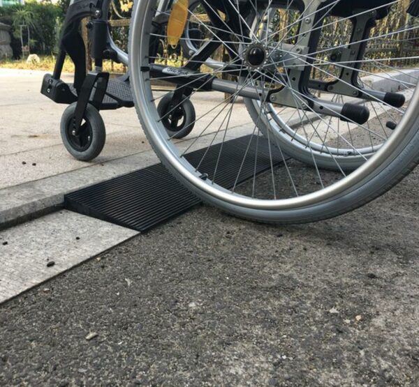 Fauteuil roulant utilisant la rampe seuil en caoutchouc de la marque identités pour franchir un trottoir